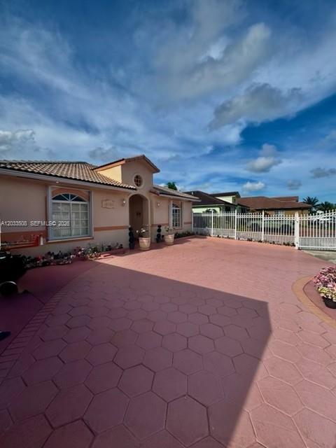 A single-story house with a pink hexagonal-patterned driveway and a white fence — 14365 SW 172nd Ln, Miami FL 33177, MIAMI, FL