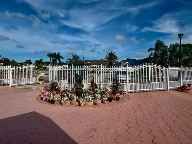 A white metal gate opens to a circular driveway with a central flower bed — 14365 SW 172nd Ln, Miami FL 33177, MIAMI, FL
