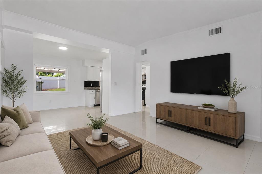 A living room with a sofa, coffee table, and wall-mounted television over a wooden console — 5910 INDIAN HILL ROAD, ORLANDO, FL