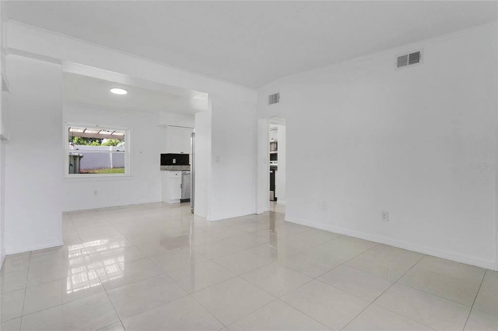 A bright, open-concept living area with white walls and light-colored tile flooring — 5910 INDIAN HILL ROAD, ORLANDO, FL