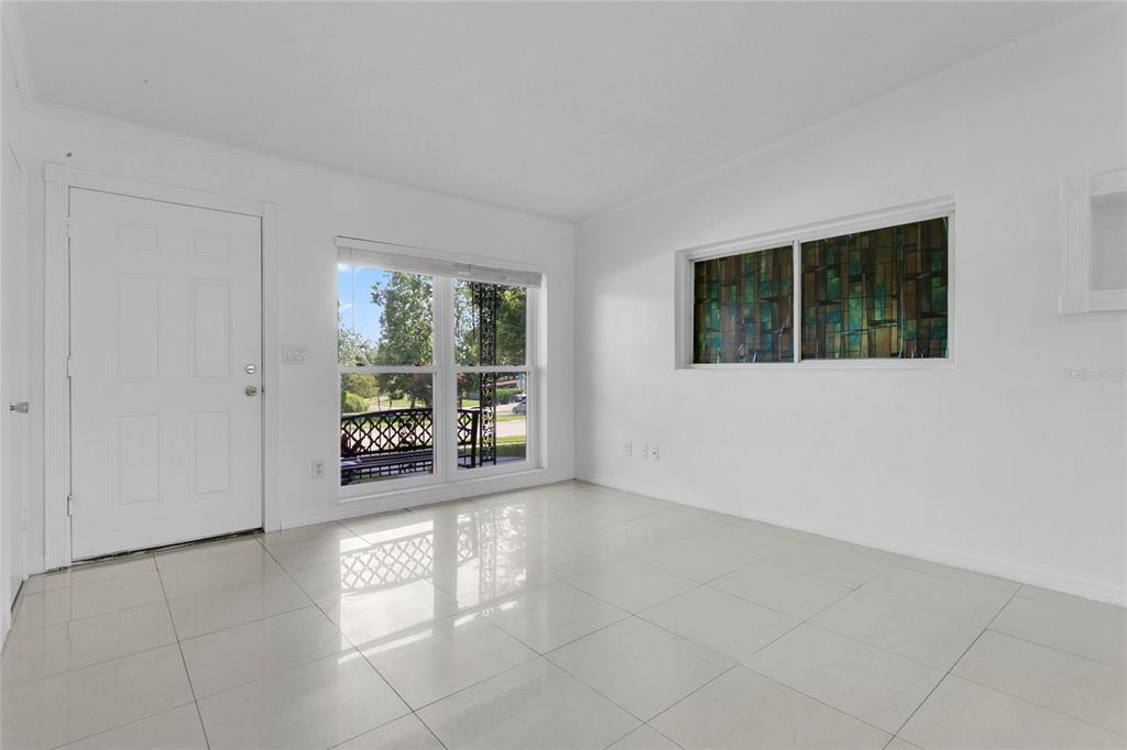 A bright room with white walls, white tile flooring, a front door, and stained-glass windows — 5910 INDIAN HILL ROAD, ORLANDO, FL