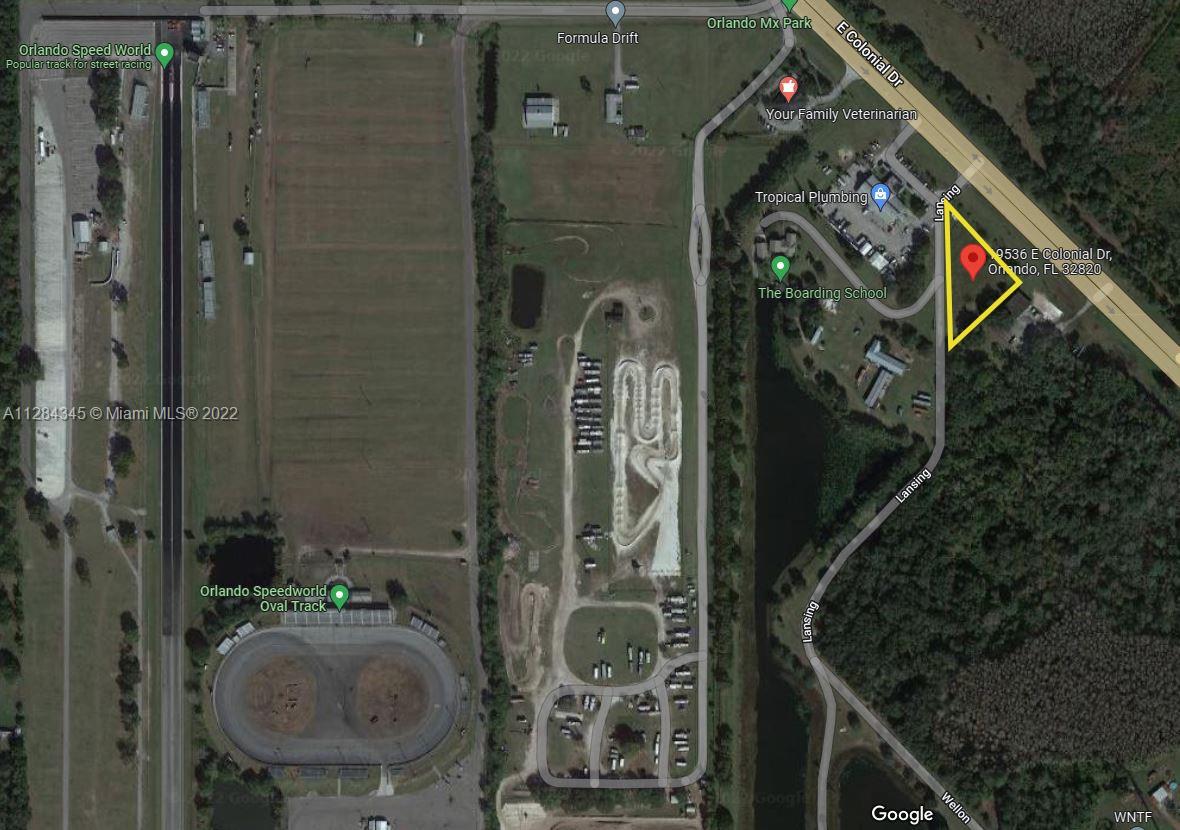 This is a satellite map view of a property lot outlined in yellow near a racetrack — 19536 E Colonial Dr, Orlando FL 32820, ORLANDO, FL