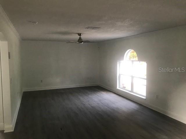 An empty room with gray wood-look flooring, a ceiling fan, and an arched window — 139 OAK VIEW PLACE, SANFORD, FL