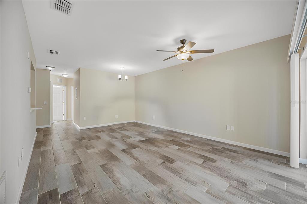 A living room with light-colored walls, wood-look tile flooring, and a ceiling fan — 1195 GODAVARI WAY E UNIT 201, WESLEY CHAPEL, FL