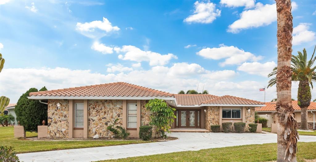 A single-story house with a stone facade, tile roof, and a large concrete driveway — 3734 TOPSAIL TRAIL, NEW PORT RICHEY, FL