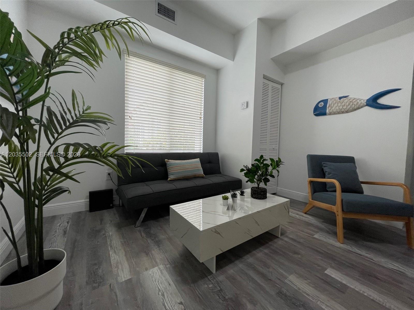A living room features a gray futon, a marble-patterned coffee table, and a blue armchair — 29 Oviedo Ave # 1, Coral Gables FL 33134, CORAL GABLES, FL