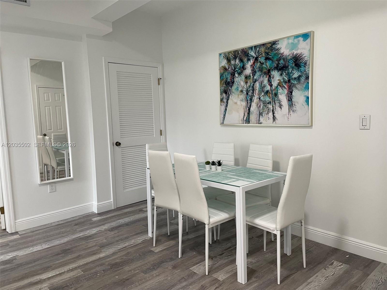 A dining room features a white table with four chairs, a palm tree painting, and flooring — 29 Oviedo Ave # 1, Coral Gables FL 33134, CORAL GABLES, FL