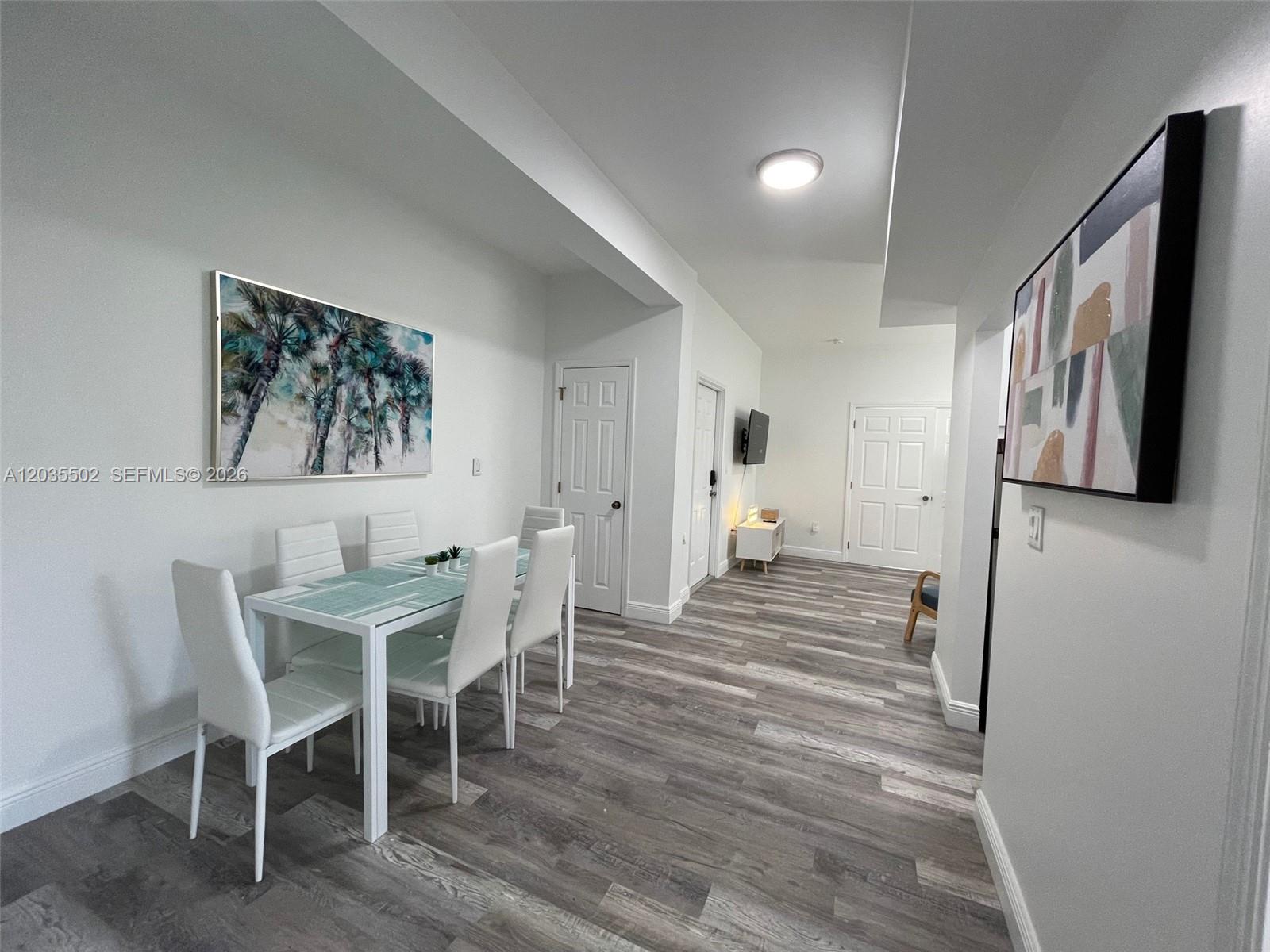 A dining area with a glass table and chairs sits in a room with wood-look flooring — 29 Oviedo Ave # 1, Coral Gables FL 33134, CORAL GABLES, FL