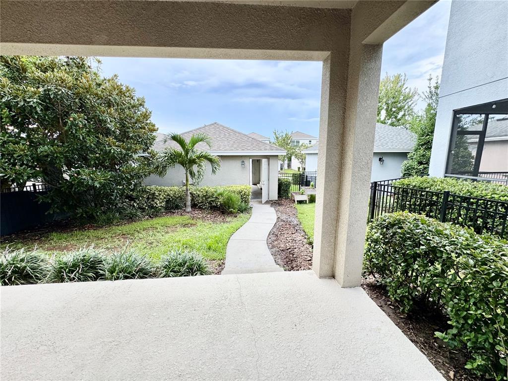 A concrete patio overlooks a backyard with a walkway leading to a detached garage — 7208 MILESTONE DRIVE, APOLLO BEACH, FL