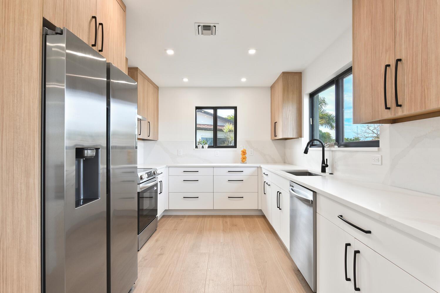 A modern kitchen features light wood cabinets, white countertops, stainless steel appliances, and a window — 1320 S Deerfield Avenue, Deerfield Beach FL 33441, DEERFIELD BEACH, FL