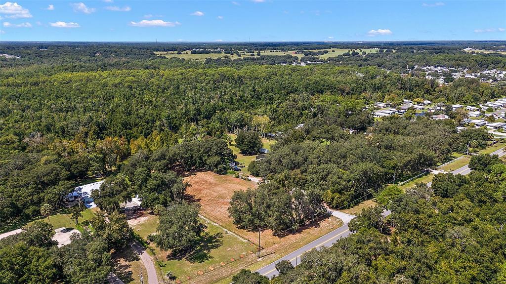 An aerial view shows a cleared rectangular lot surrounded by dense trees and a road — LAKE UNITY ROAD, FRUITLAND PARK, FL