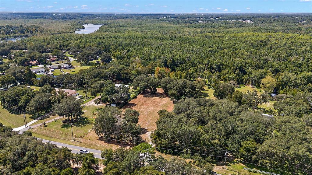 An aerial view shows a cleared rectangular lot surrounded by dense trees and nearby houses — LAKE UNITY ROAD, FRUITLAND PARK, FL
