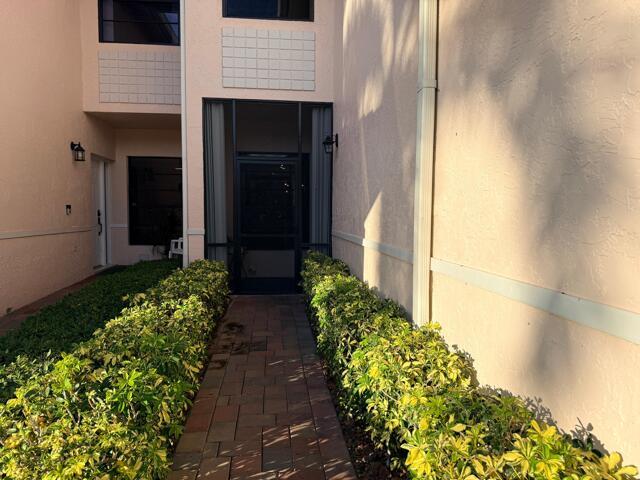A brick walkway leads to a screened front entryway flanked by hedges and stucco walls — 8659 Vía Reale # 1, Boca Raton FL 33496, BOCA RATON, FL