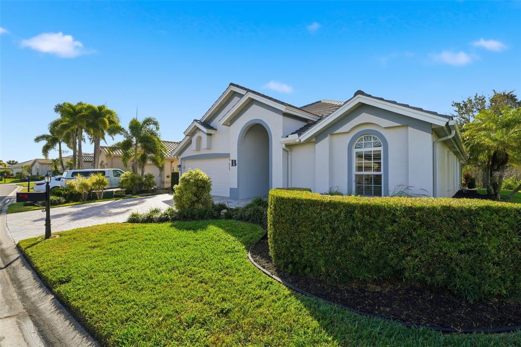 A single-story house with a white stucco exterior, arched entryway, and a manicured hedge — 3401 BAY RIDGE WAY, PORT CHARLOTTE, FL