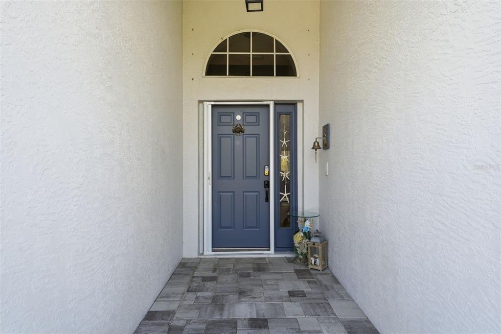 A blue front door with a sidelight is centered in a covered entryway — 3401 BAY RIDGE WAY, PORT CHARLOTTE, FL