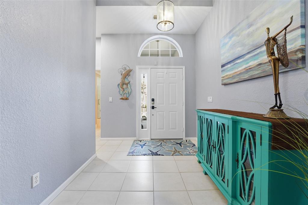 A bright entryway features light tile flooring, a white front door, and a turquoise console table — 3401 BAY RIDGE WAY, PORT CHARLOTTE, FL