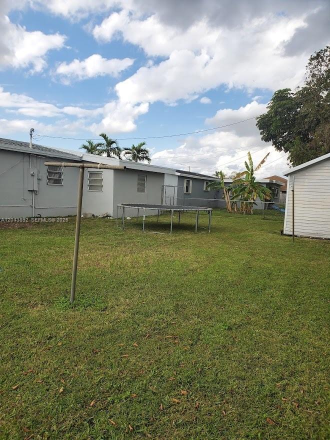 A grassy backyard features a trampoline, a clothesline, and a view of neighboring houses — 14721 SW 104th Ave, Miami FL 33176, MIAMI, FL