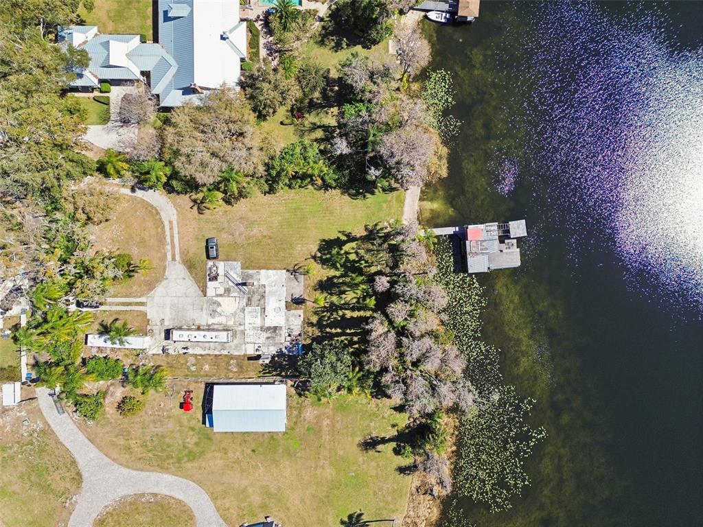An aerial view shows a waterfront property with a house, outbuildings, and a boat dock — 16515 LAKE CHURCH DRIVE, ODESSA, FL