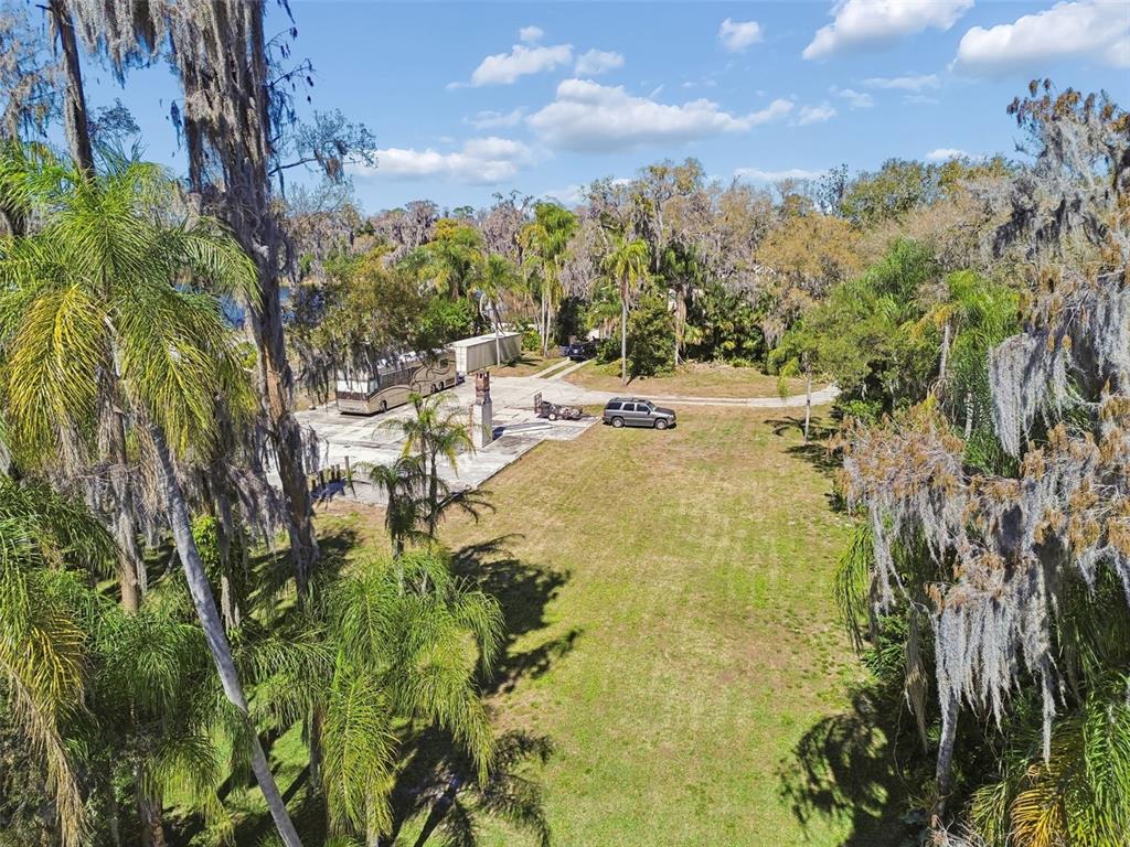An aerial view shows a grassy lot with a concrete pad, RV, and parked car — 16515 LAKE CHURCH DRIVE, ODESSA, FL