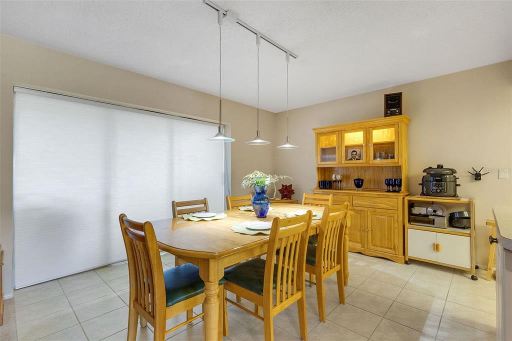 A dining room features a wooden table and hutch, tile flooring, and three pendant lights — 1518 70TH STREET W, BRADENTON, FL