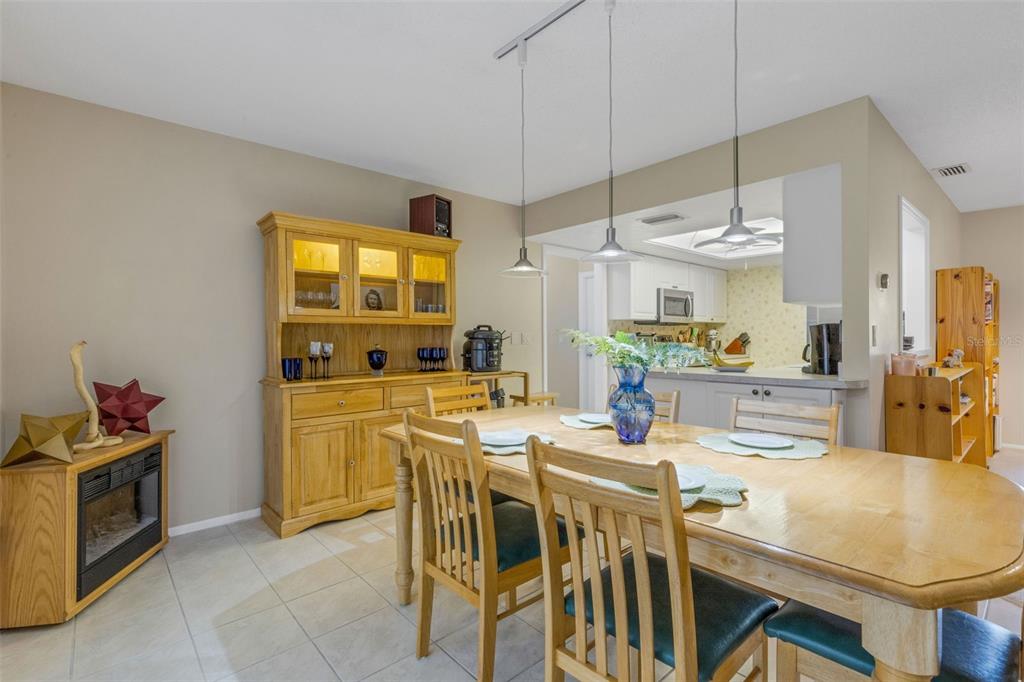 A dining room features a wooden hutch, a table with chairs, and an adjacent kitchen — 1518 70TH STREET W, BRADENTON, FL