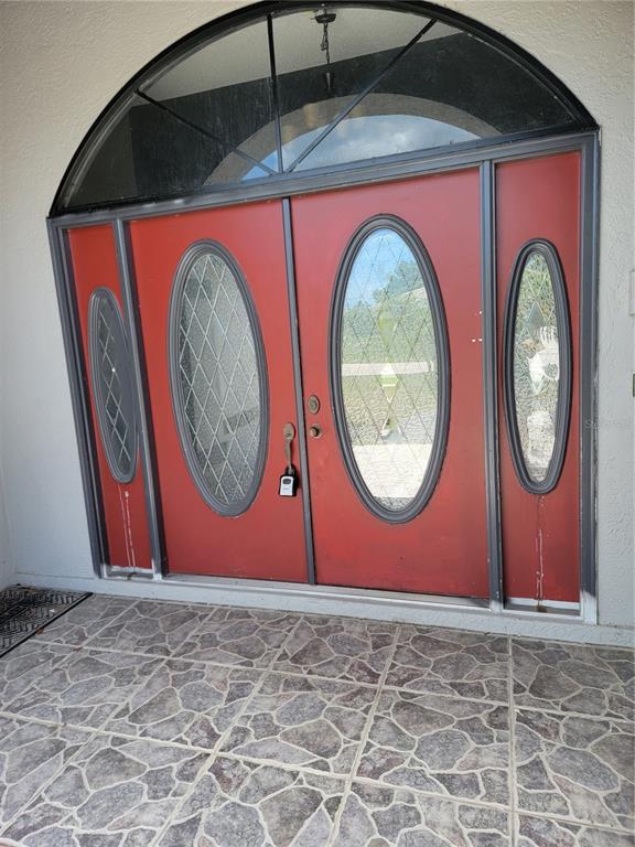 A red double front door with oval glass inserts and a large arched transom window — 5990 GILLOT BOULEVARD, PORT CHARLOTTE, FL