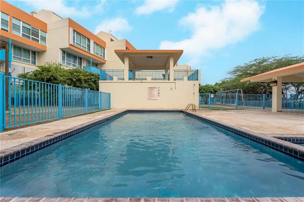 A rectangular swimming pool sits in front of a multi-story building with a covered patio — PR-301 CONDO. VISTAMAR EL COMBATE UNIT B-207, CABO ROJO, PR