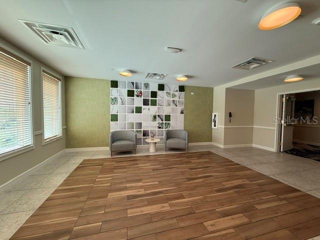 A room with wood-look tile flooring, two armchairs, and a decorative wall feature — 8061 VACATION AVENUE UNIT 216, KISSIMMEE, FL