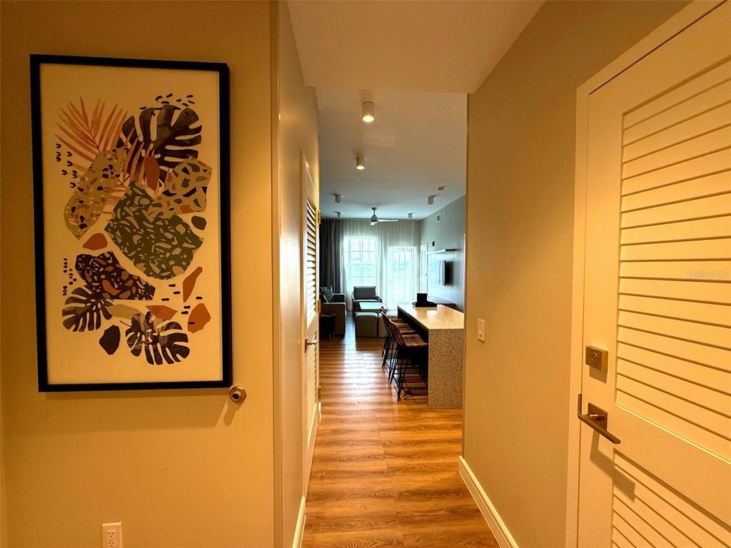 A hallway leads into an open-concept living area with a kitchen island and wood flooring — 8061 VACATION AVENUE UNIT 216, KISSIMMEE, FL