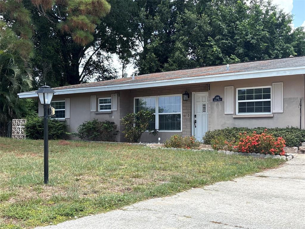A single-story house with a gray exterior, a white front door, and a concrete driveway — 3341 ANDREA STREET, SARASOTA, FL