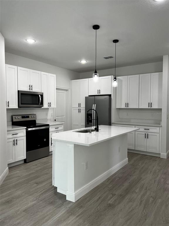 A modern kitchen features white cabinets, stainless steel appliances, and a central island with seating — 3 FISHER PLACE DRIVE, OCKLAWAHA, FL