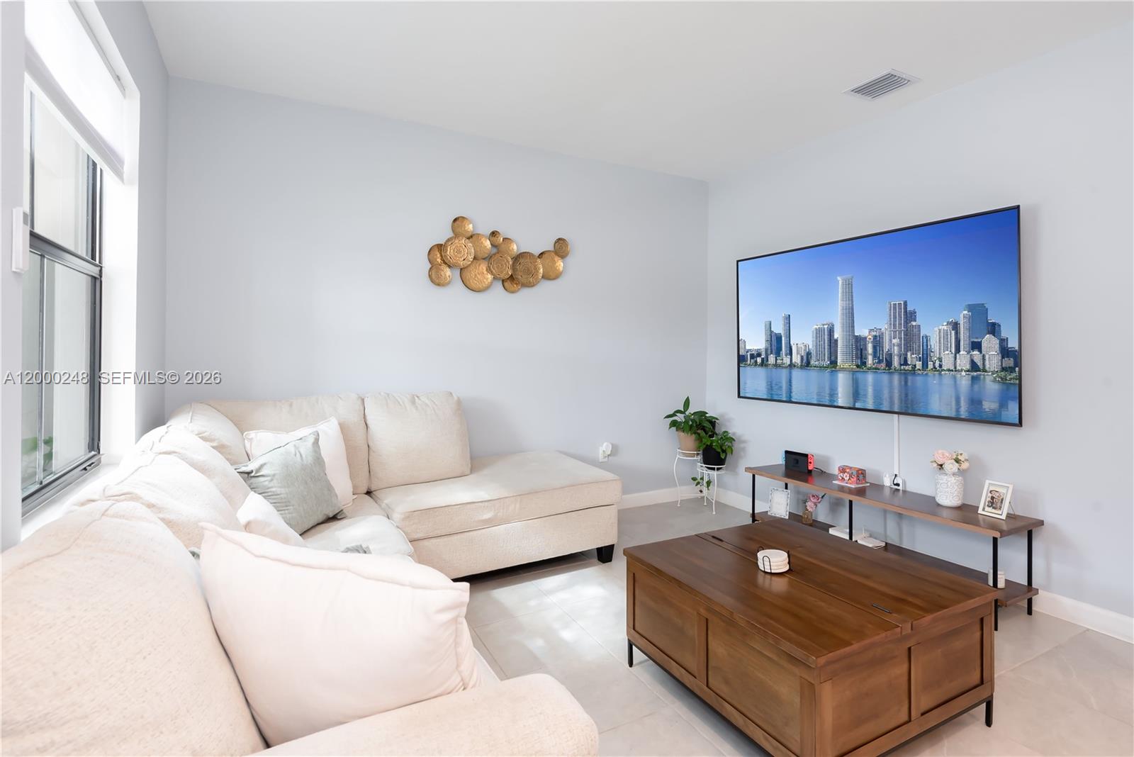 A living room features a sectional sofa, a wooden coffee table, and a wall-mounted television — 23129 SW 99th Ave, Cutler Bay FL 33190, CUTLER BAY, FL