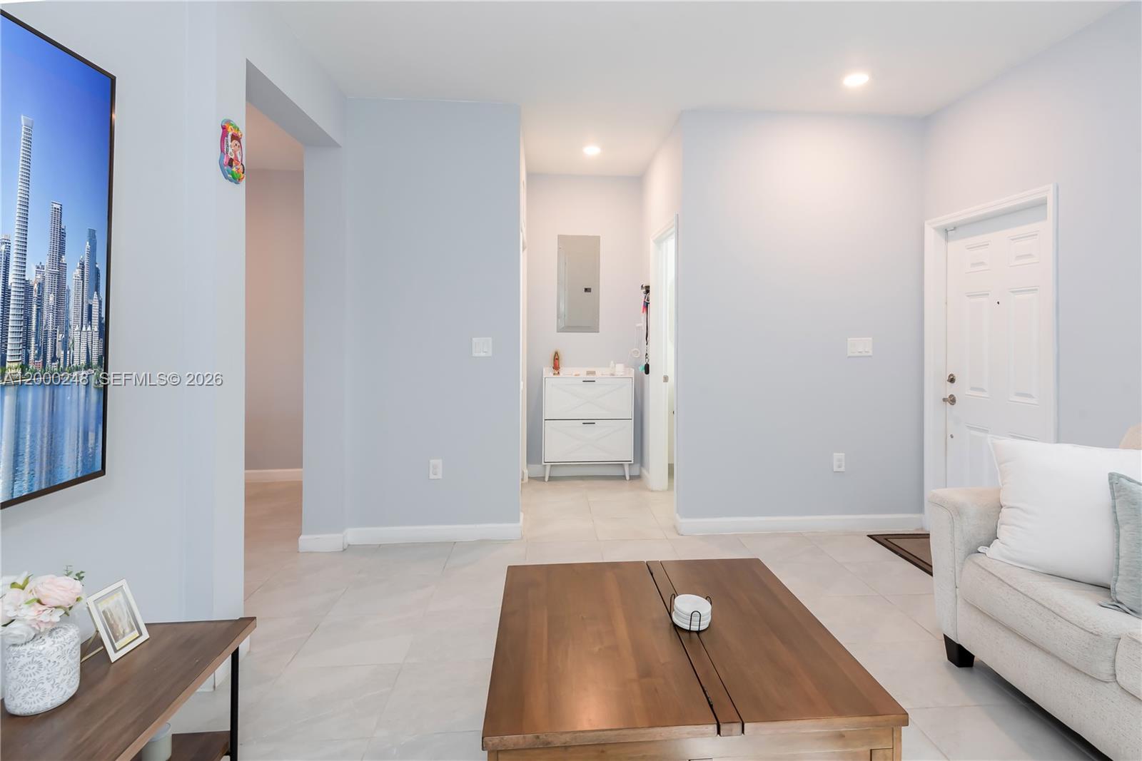 A living room features light blue walls, tile flooring, a wooden coffee table, and a television — 23129 SW 99th Ave, Cutler Bay FL 33190, CUTLER BAY, FL