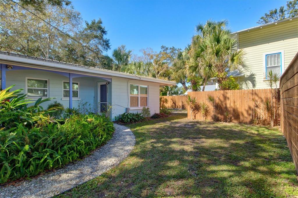 A light blue house with a gravel path, green lawn, and a wooden privacy fence — 1751 6TH STREET, SARASOTA, FL