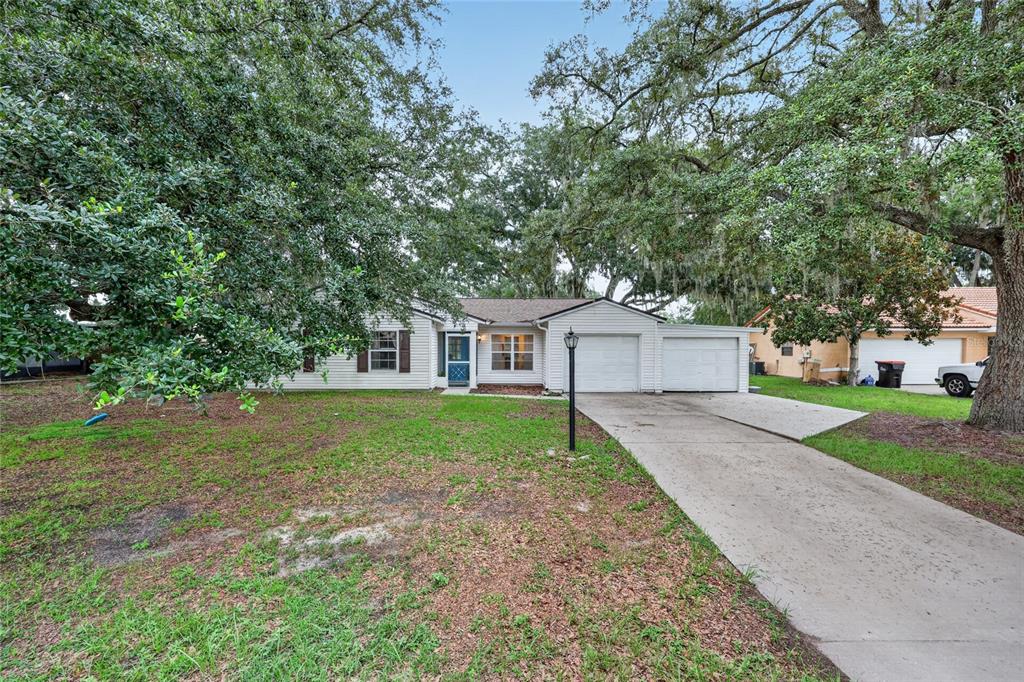 A single-story house with a two-car garage, white siding, and a large front yard — 303 OAK TRACK PASS, OCALA, FL