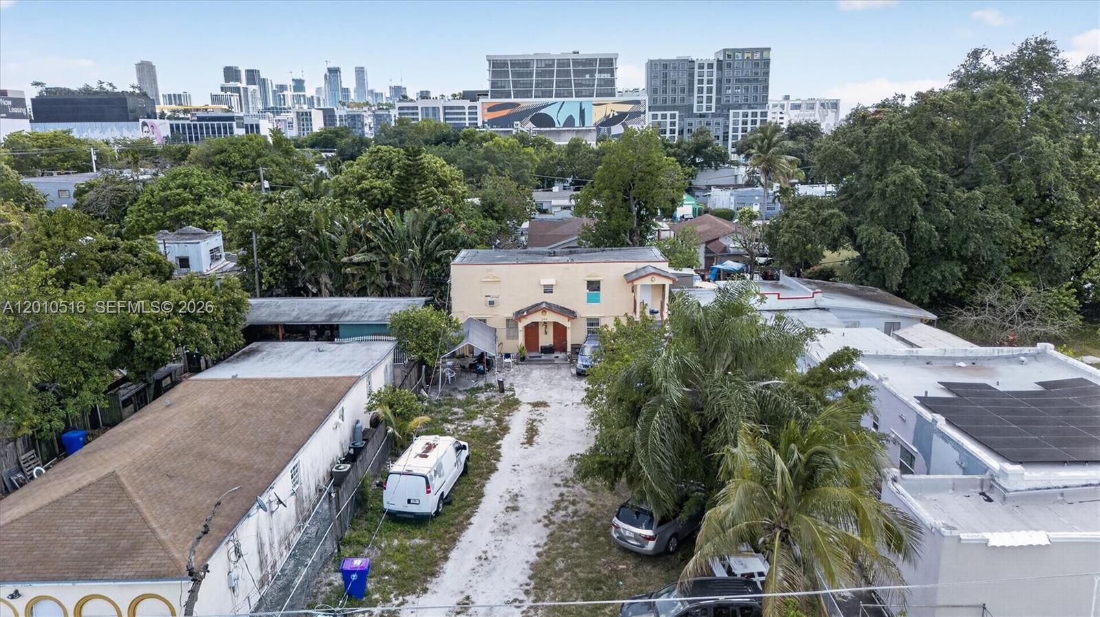 An aerial view shows a two-story beige building with a gravel driveway and surrounding trees — 244 NW 32nd St, Miami FL 33127, MIAMI, FL