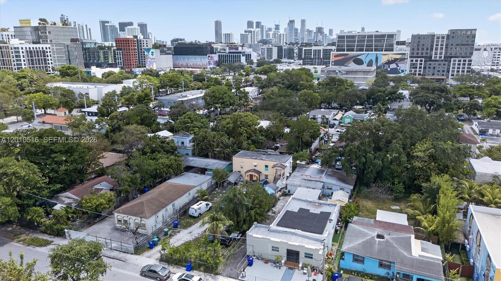 An aerial view shows residential houses and trees in front of a distant city skyline — 244 NW 32nd St, Miami FL 33127, MIAMI, FL