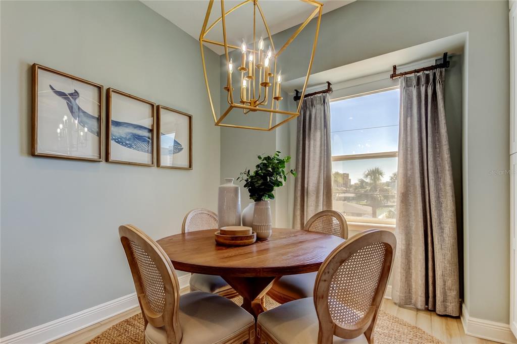 A dining area features a round wooden table, cane-back chairs, and a geometric gold chandelier — 120 BRIGHTWATER DRIVE UNIT 5, CLEARWATER, FL