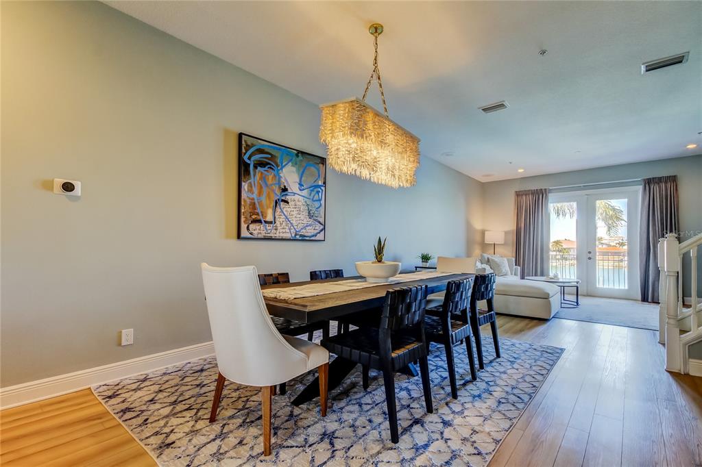 A dining room features a rectangular table, black chairs, a chandelier, and a patterned rug — 120 BRIGHTWATER DRIVE UNIT 5, CLEARWATER, FL
