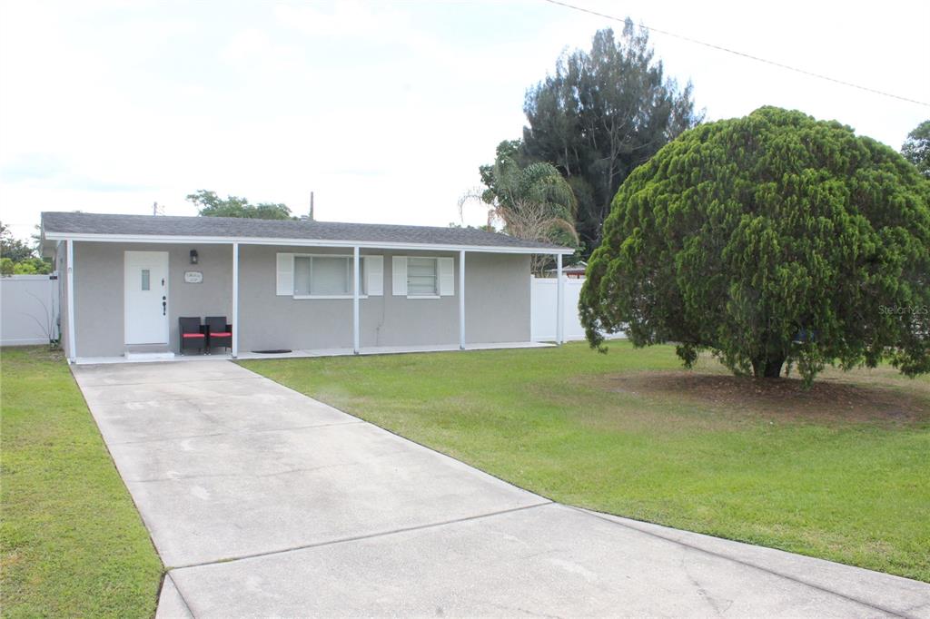 A single-story gray house with a white door, a concrete driveway, and a large tree — 307 CALIFORNIA AVENUE, ST CLOUD, FL