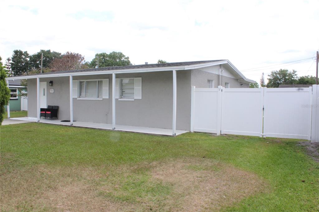 A single-story house with a covered porch and a white vinyl fence in the yard — 307 CALIFORNIA AVENUE, ST CLOUD, FL