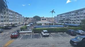 An exterior view of a multi-story apartment complex with a parking lot and swimming pool — 215 SE 3rd Ave # 101A, Hallandale Beach FL 33009, HALLANDALE BEACH, FL