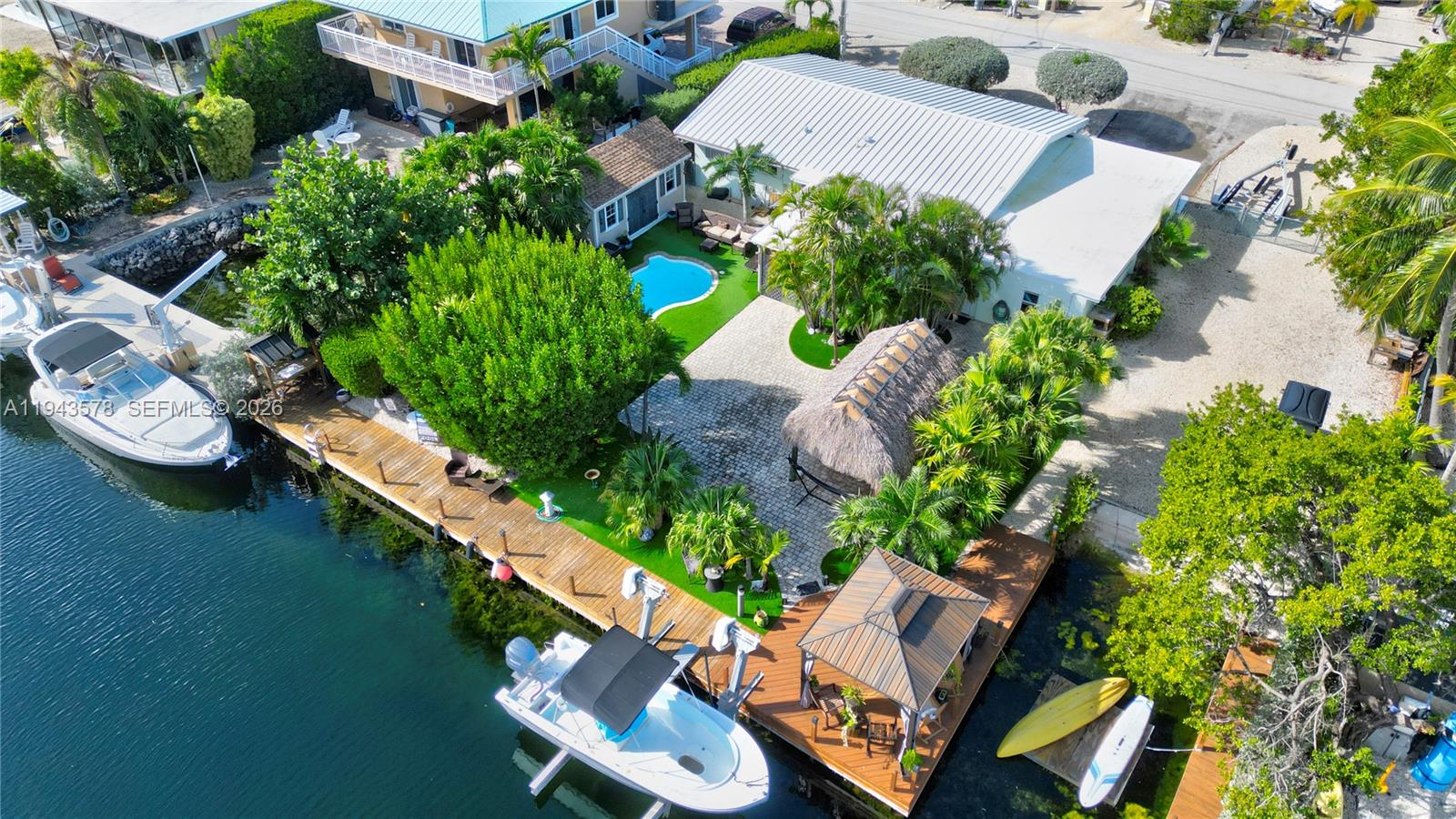 An aerial view shows a waterfront property with a house, pool, gazebo, and two boats — 150 Azalea St., Plantation Key FL 33070, PLANTATION KEY, FL