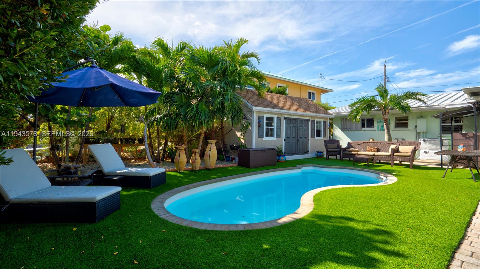 A backyard features a kidney-shaped swimming pool, lounge chairs, a shed, and patio furniture — 150 Azalea St., Plantation Key FL 33070, PLANTATION KEY, FL