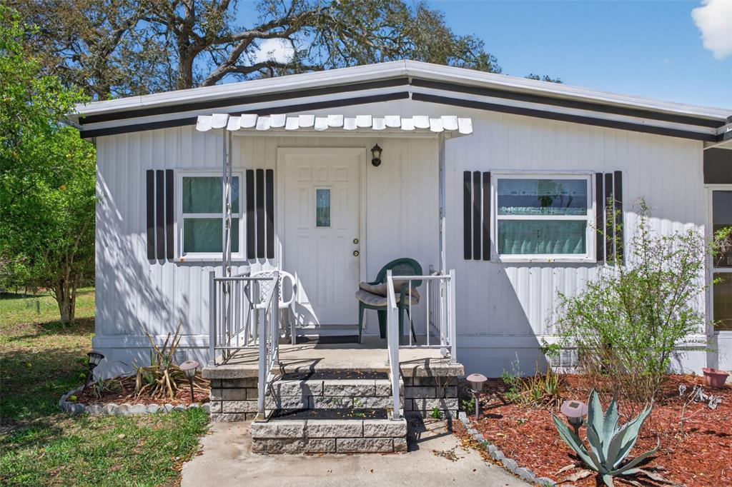A white mobile home with a small front porch, concrete steps, and two windows — 7489 WESTERN CIRCLE DRIVE, BROOKSVILLE, FL
