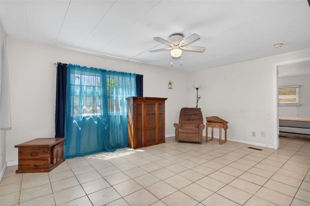 A living room with white walls, tile flooring, a ceiling fan, and blue curtains — 7489 WESTERN CIRCLE DRIVE, BROOKSVILLE, FL