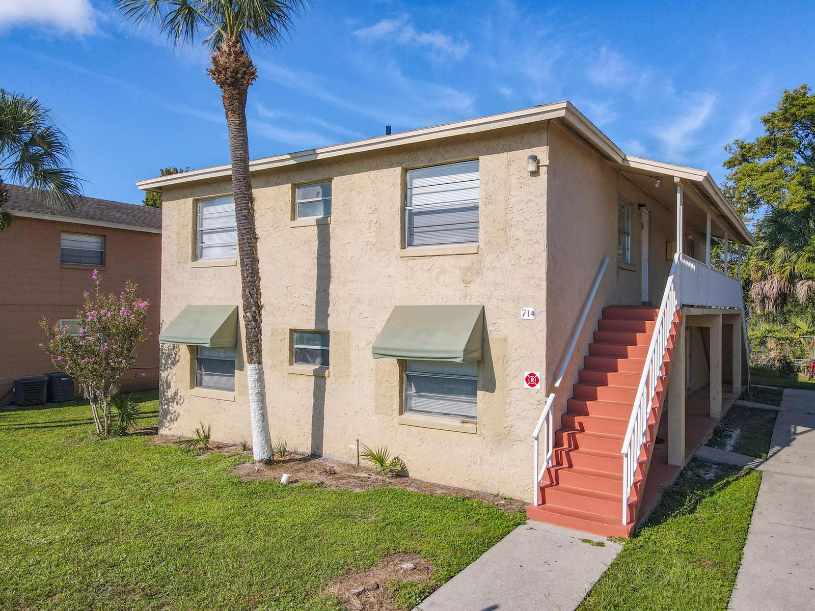 A two-story tan apartment building features an exterior staircase and a palm tree — 714 Michigan Court # 4, FL 34769, FL