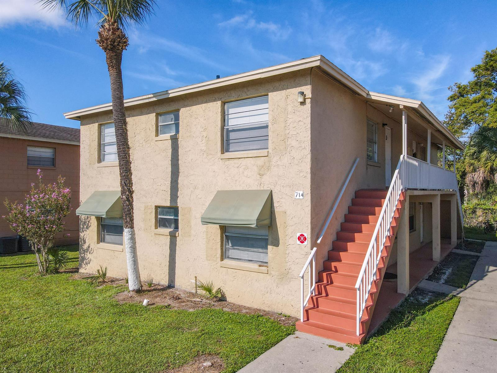 A two-story tan apartment building features an exterior staircase and green window awnings — 714 Michigan Court # 4, FL 34769, FL