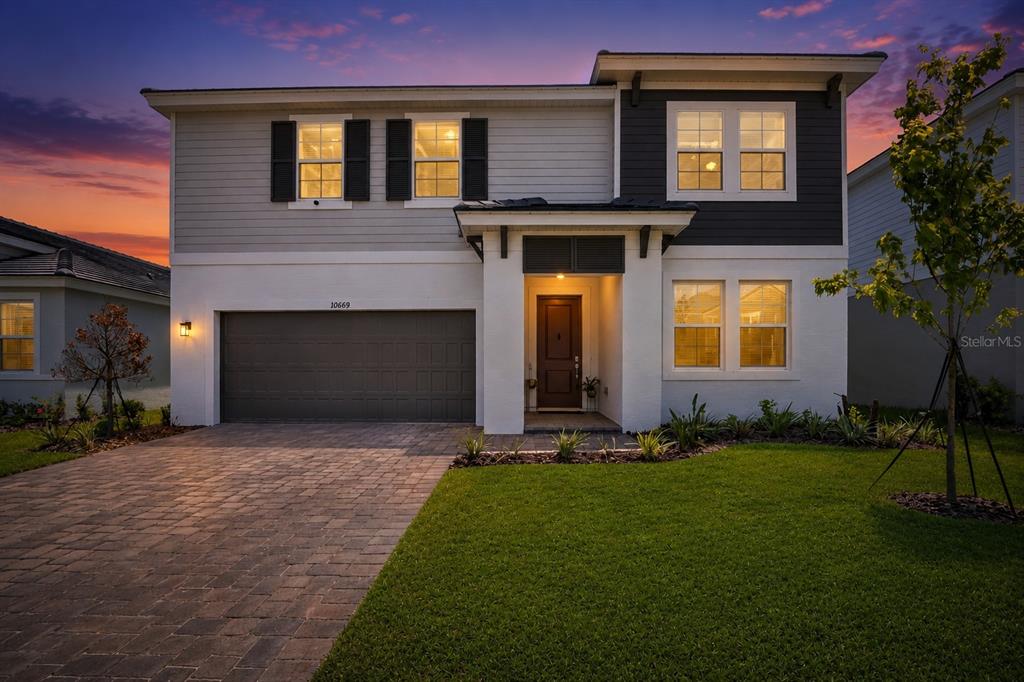 A two-story house with a white stucco lower level, gray siding, and a paved driveway — 10009 SURREY ROSE DRIVE, SAN ANTONIO, FL