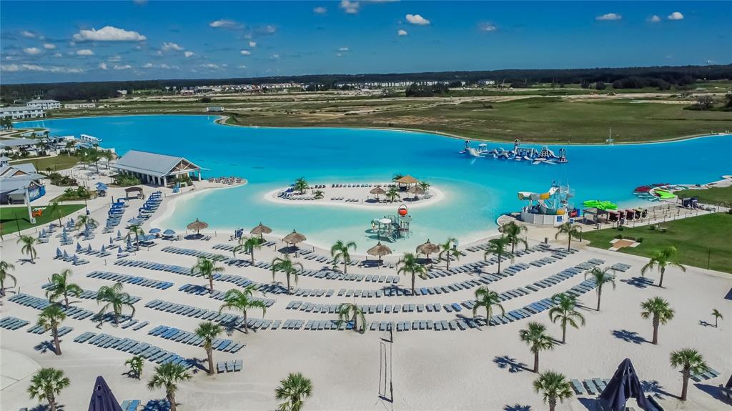 An aerial view shows a large turquoise lagoon with a sandy beach and water slides — 10009 SURREY ROSE DRIVE, SAN ANTONIO, FL